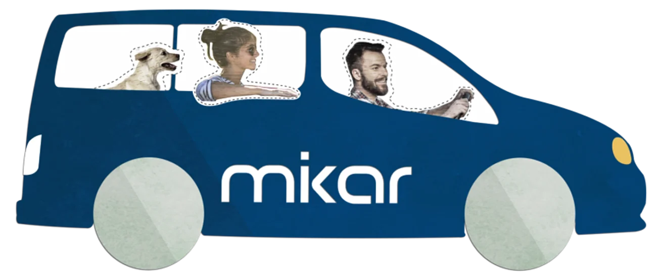 Blaues Auto mit zwei Personen und einem Hund, auf dem Auto der Schriftzug "mikar" auf der Seite. Fahrer hält das Lenkrad.