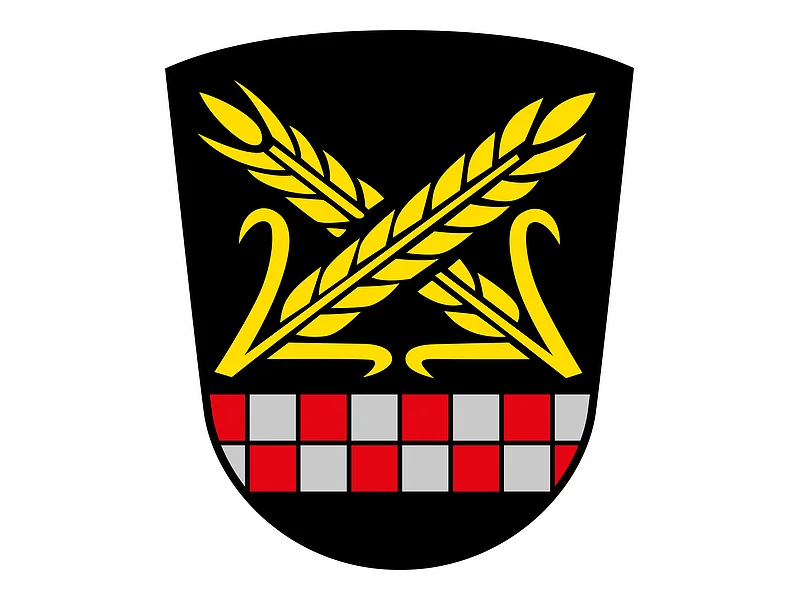 Das Wappen des Monheimer Stadtteils Itzing. Wappen mit zwei gekreuzten goldenen Ähren über einem rot-silbernen Schachbrettmuster auf schwarzem Hintergrund.