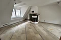 Miet-Maisonette - Kachelofen im Obergeschoss (Wohn-/Schlafraum) Miet Maisonette Marktplatz. Leerer Raum mit hellen Bodenfliesen, weiß gestrichenen Wänden, Dachfenster und grün-weißer Kachelofen in der Ecke.