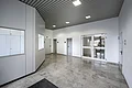 Appl Bürogebäude Innenaufnahme 8 Leerer heller Flur mit grauem Marmorboden, weißen Wänden, mehreren Türen und Deckenleuchten. Links im Bild eine weiße Wand zur Abtrennung in einen kleinen Empfangsbereich.