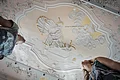 Stuckdecke im Monheimer Rathaus mit barocker farbiger Stuckreliefdarstellung und zwei Personen, die von unten darauf schauen.