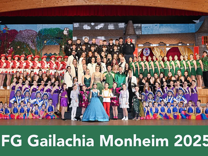 Gruppenfoto von FG Gailachia Monheim 2025 mit vielen Personen in bunten Kostümen auf einer Bühne vor einem Bühnenbild.