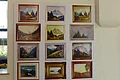 Drucke des Kunstmalers Hans Mayer Wand mit zwölf gerahmten Landschaftsbildern, hauptsächlich Berge, Wälder und Häuser.