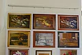 Bilder von Hans Mayer Weiße Wand mit Aufhänge-Befestigung, darunter elf gerahmten Gemälde des Kunstmalers Hans Mayer, darunter Enten, Landschaften, Blumen und Porträts.